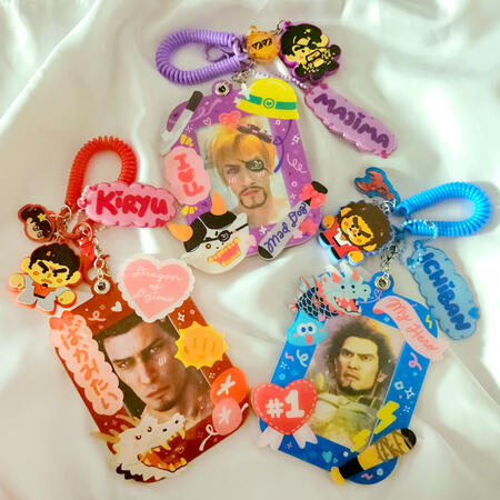 Acrylic photocard holders, puffy charms, PVC rubber keychains, and acrylic keychains inspired by the Yakuza series. All sets are assembled by hand by me! Photocards pictured are not for sale but are present for demonstration purposes.